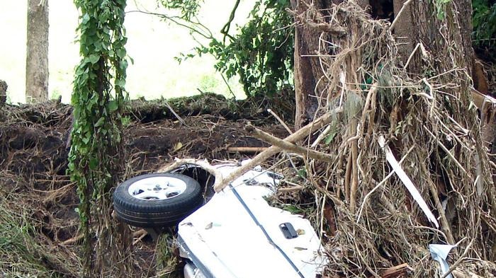 A car smashed and tangled in debris at Withcott