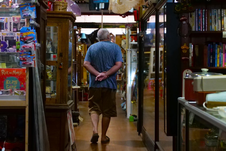 A man browses from floor to ceiling in an emporium filled with strange items.
