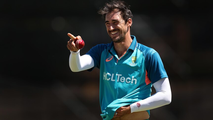 Mitch Starc smiles and points