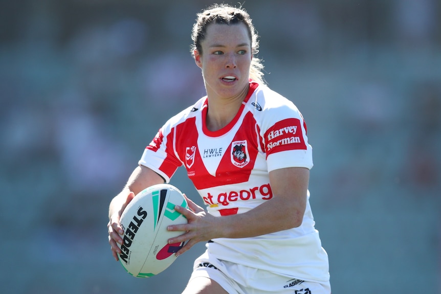 A St George Illawarra NRLW player holds the ball in two hands during a match.