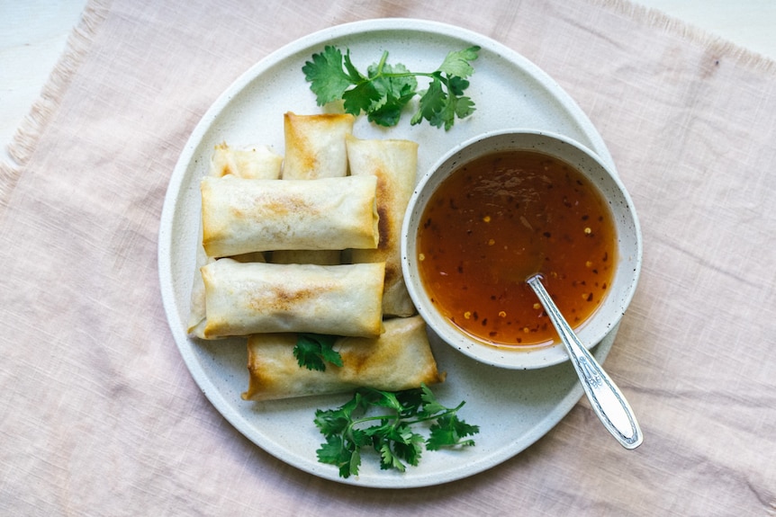 A plate of baked spring rolls with homemade sweet chilli dipping sauce.