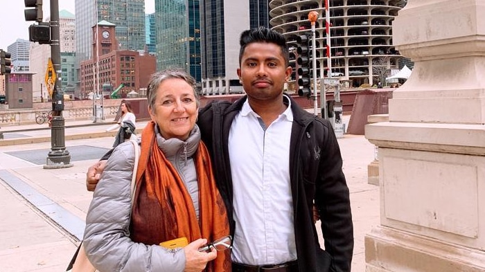 Faisal Parvez stands next to his teacher in front of skyscrapers.
