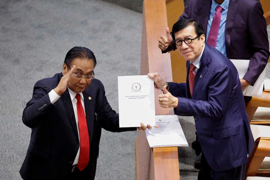 One politician salutes as he recieves a report from another on the floor of parliament.