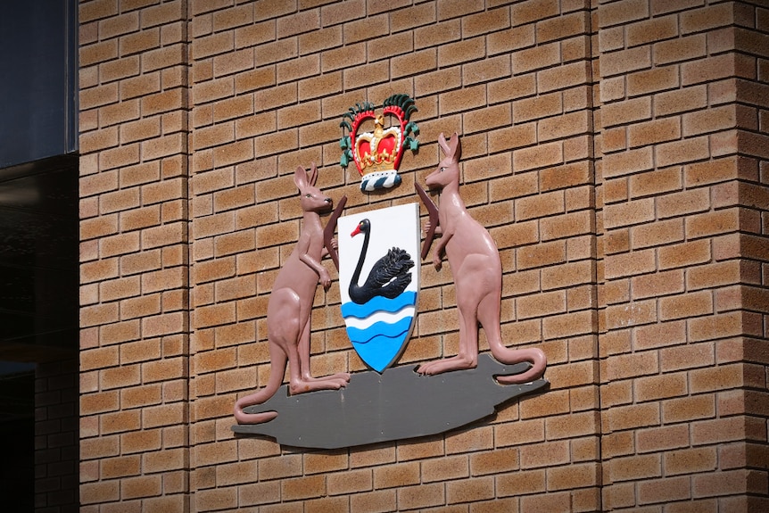 The Western Australian justice logo of a kangaroo and swan depicted on the side of a brown brick wall
