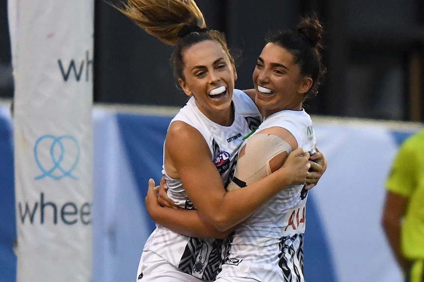 Two Collingwood AFLW players embrace as they celebrate a goal against Carlton.