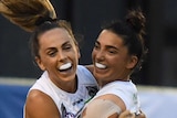 Two Collingwood AFLW players embrace as they celebrate a goal against Carlton.