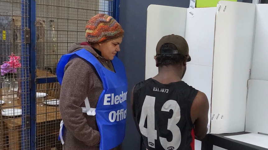 An APY Lands electoral officer helps a resident with his vote at a polling booth.