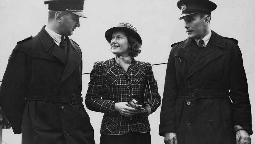 Australian aviator Nancy Bird Walton chatting with two men.