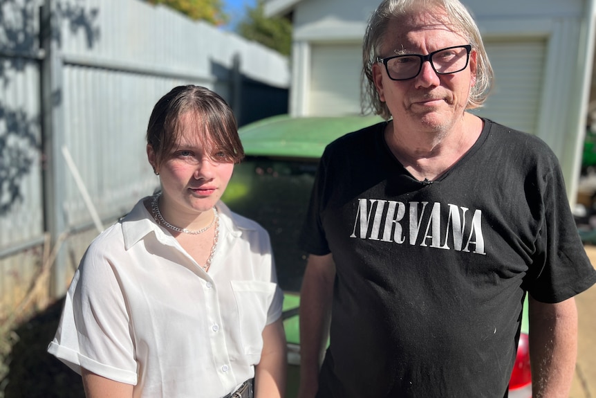 A white middle aged man and his teenage daughter standing in front of a green car