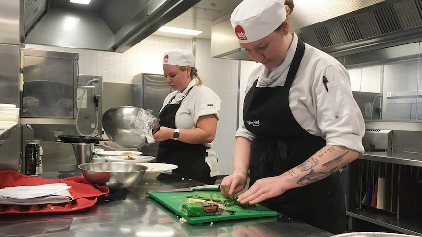 Two TAFE apprentice chefs cook in the kitchen.