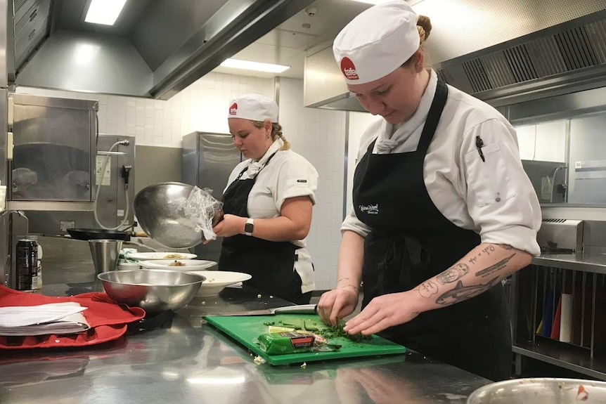 Two TAFE apprentice chefs cook in the kitchen.