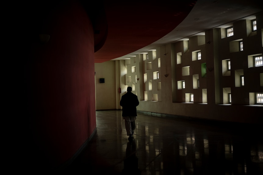 a behind shot of a man walks the dark hallways of a cinema 