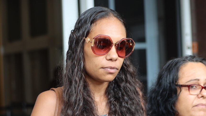 a close-up of a young woman wearing sunglasses outside court