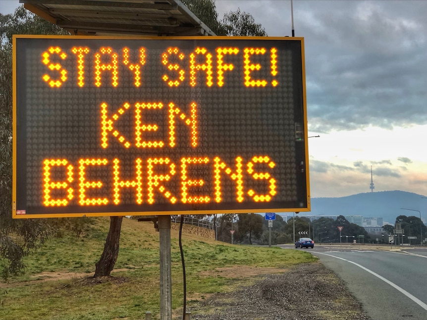 A sign on the side of a road in Canberra says 'Stay safe Ken Behrens!'
