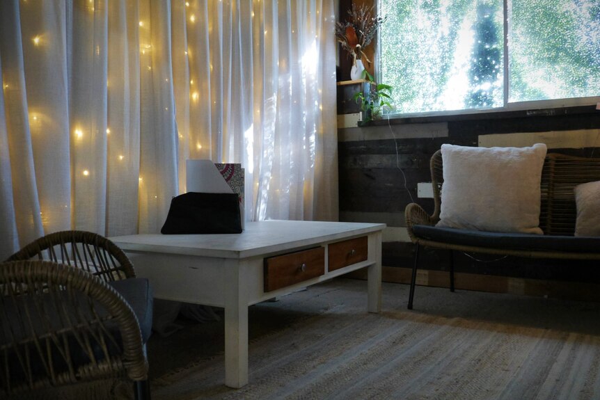 A picture of a small, cosy room. There are two chairs, a table and some fairy lights