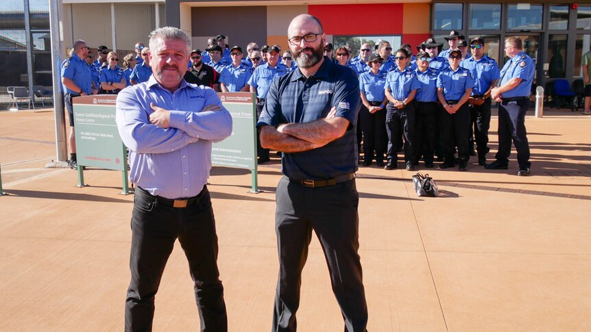 Two men stand in front of a group of striking prison officers