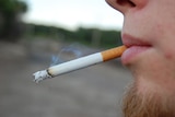 a close up side angle of the lower half of a man's face with a goatee smoking a cigarette