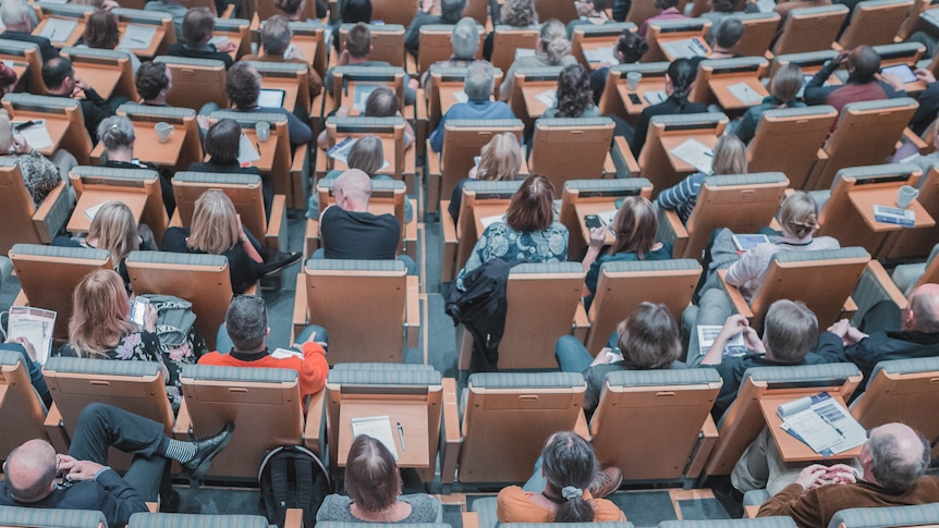 An overhead shot of university students sitting in a lecture theatre.