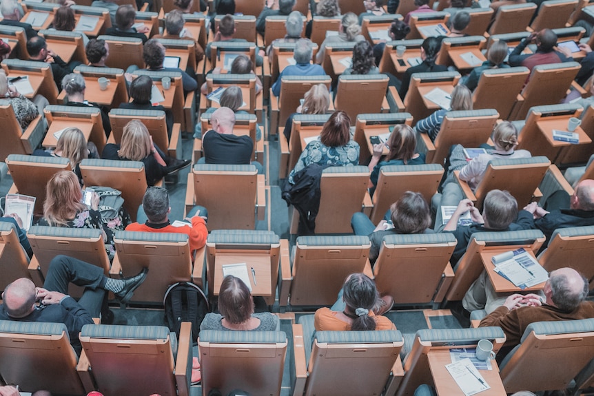 An overhead shot of university students sitting in a lecture theatre.