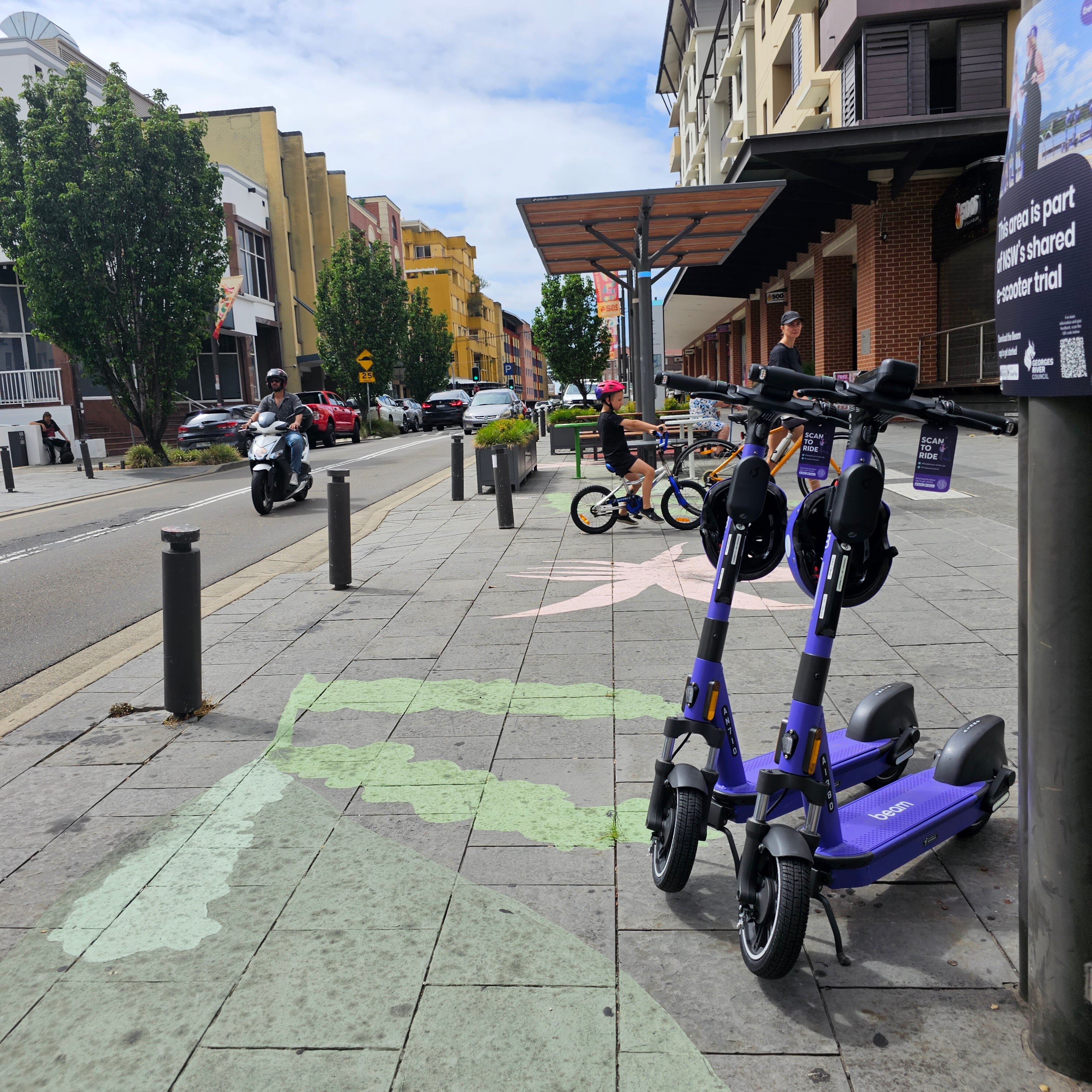 Two scooters parked by the side of a busy road 