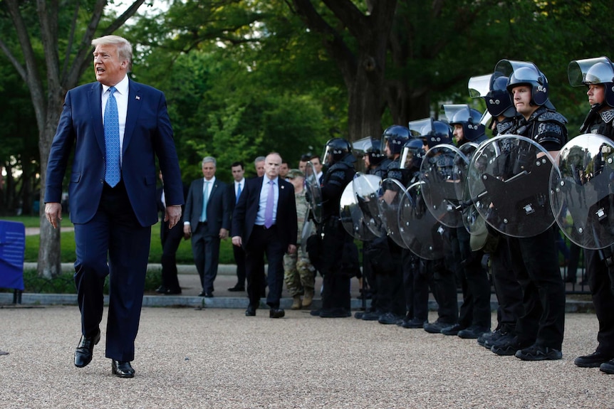 President Donald Trump walks past police in Lafayette Park.
