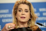 French actress Catherine Deneuve speaks into a microphone.