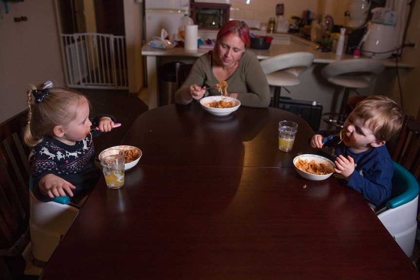 Amber, Nara and Roman sit at the dinner table eating dinner together.