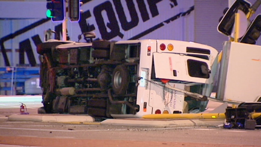 A bus lies on its side after colliding with a sedan at an intersection in Kewdale.