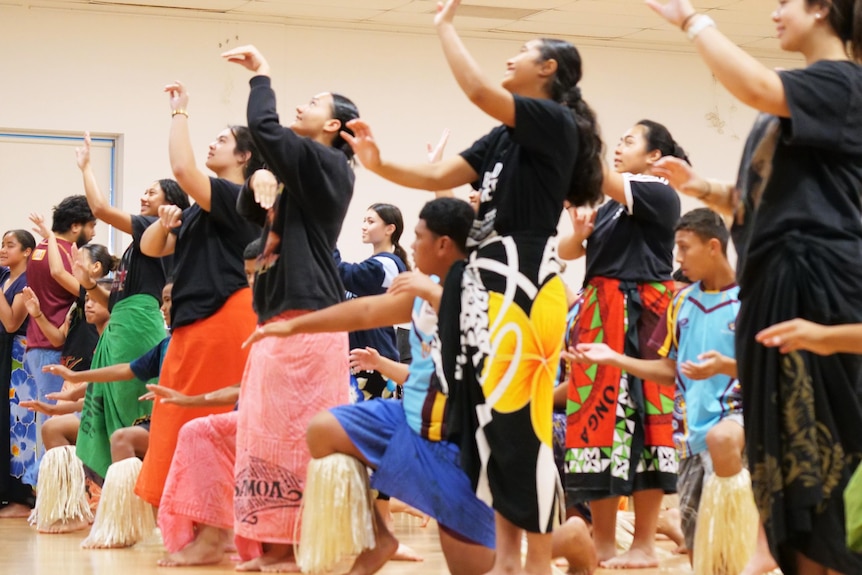 Young women and men dancing samoan dance in colourful sarongs and shirts