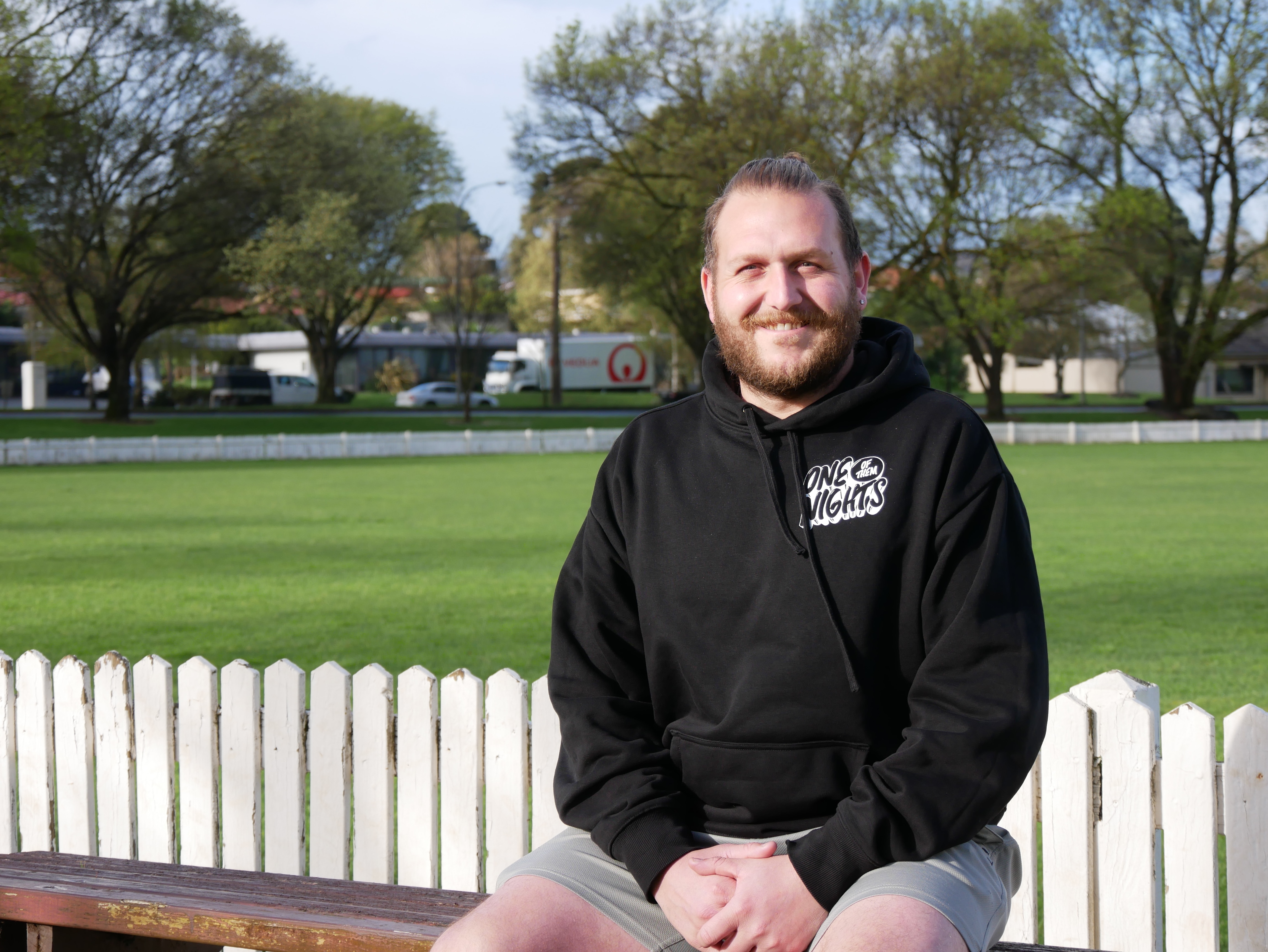 A man wearing a black jumper smiling at the camera. 