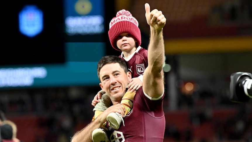 Ben Hunt gives a thumbs up while a child rides on his shoulders after State of Origin III.