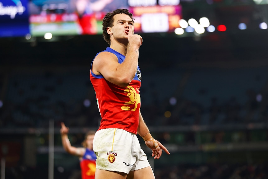 Cam Rayner holds his index finger up to his lips while facing the crowd