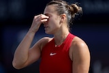 Aryna Sabalenka holds her nose during a match in Dubai as she shows her frustration.