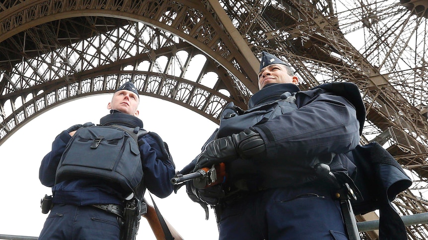 Police take up position under the Eiffel Tower the morning after a series of deadly attacks in Paris.