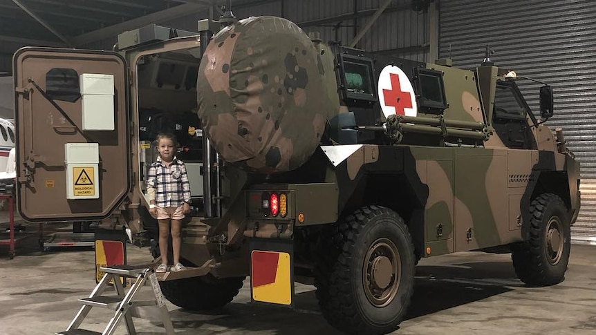 A young child stands before a Bushmaster.