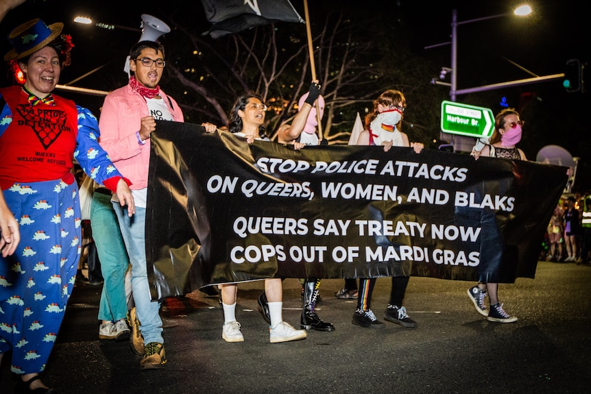 Activists carry a banner calling for a treaty and "COPS OUT OF MARDI GRAS"