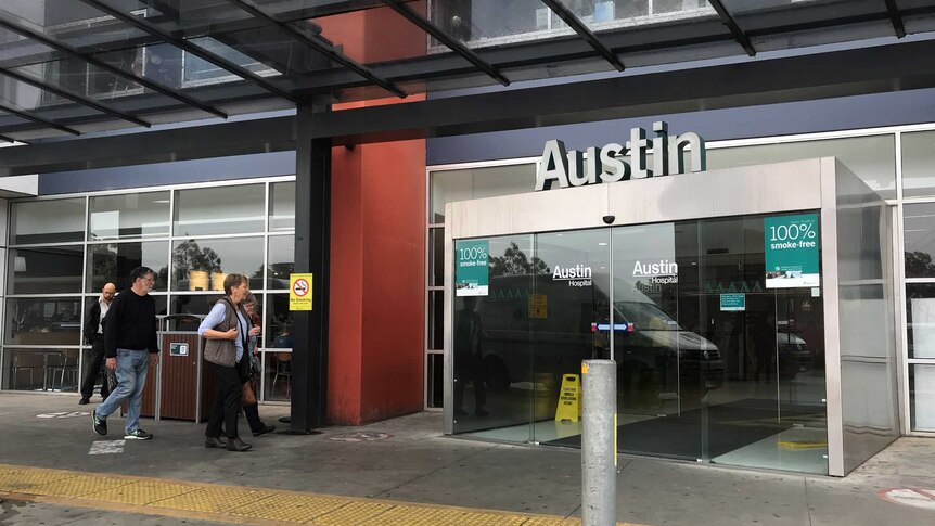 People walking outside the Austin hospital's entrance.