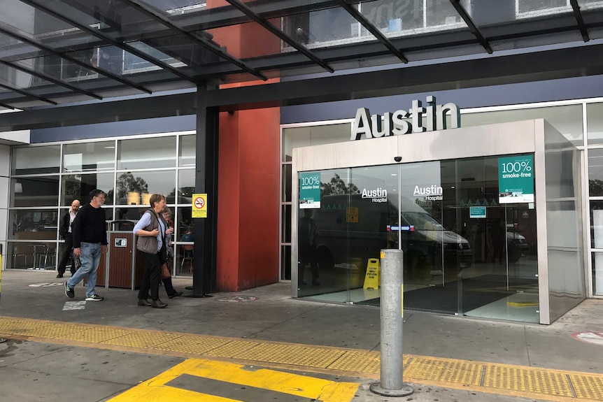 People walking outside the Austin hospital's entrance.
