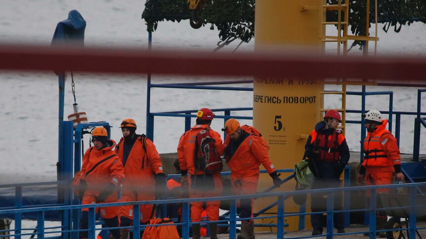 Russian Emergencies Ministry members walk on a pier near the crash site of Russian military