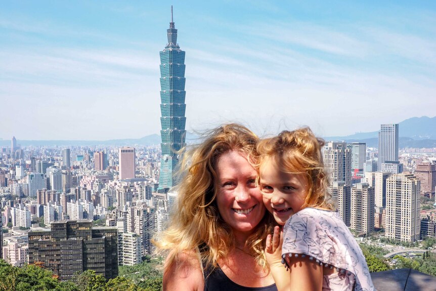 A woman and child pose for a photo overlooking Taipei.