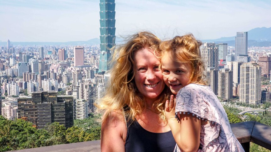 A woman and child pose for a photo overlooking Taipei.