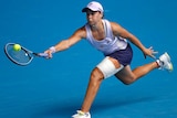 Ash Barty stretches for a forehand while wearing a bandage at the Australian Open.