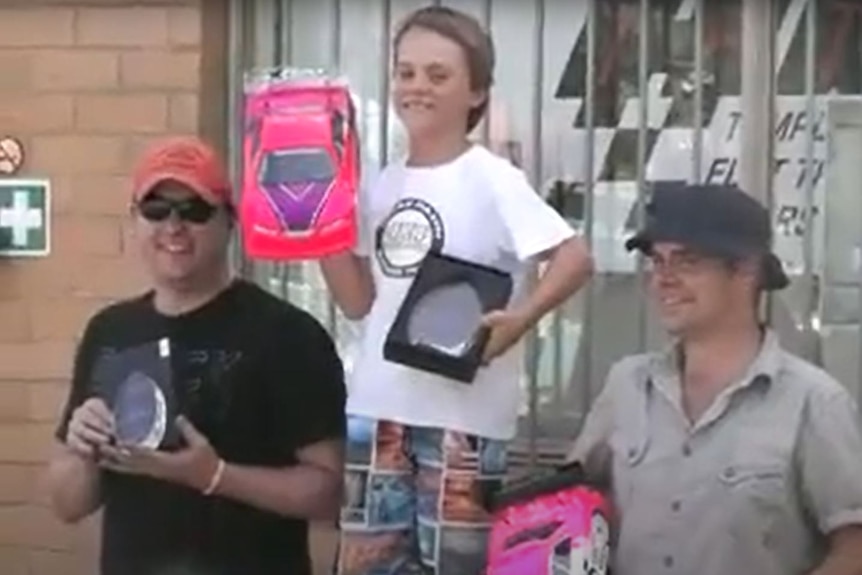 A boy and two men on a winners' podium.