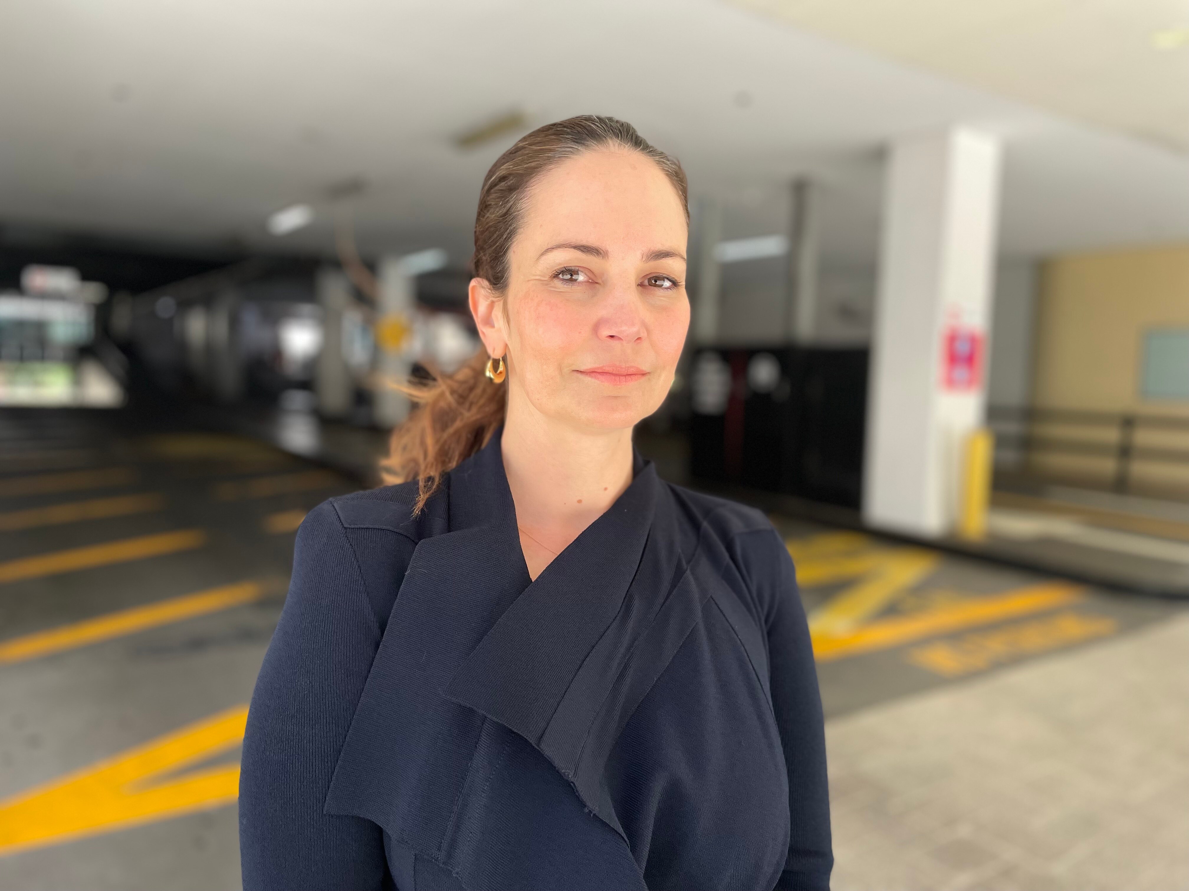 Regan Ballantine smiles slightly while standing in a carpark looking at the camera