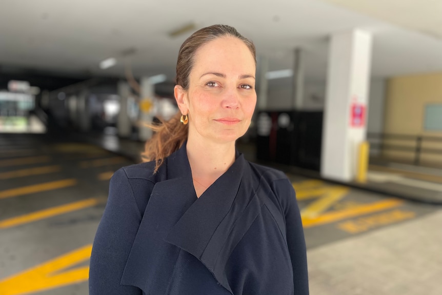 Regan Ballantine smiles slightly while standing in a carpark looking at the camera