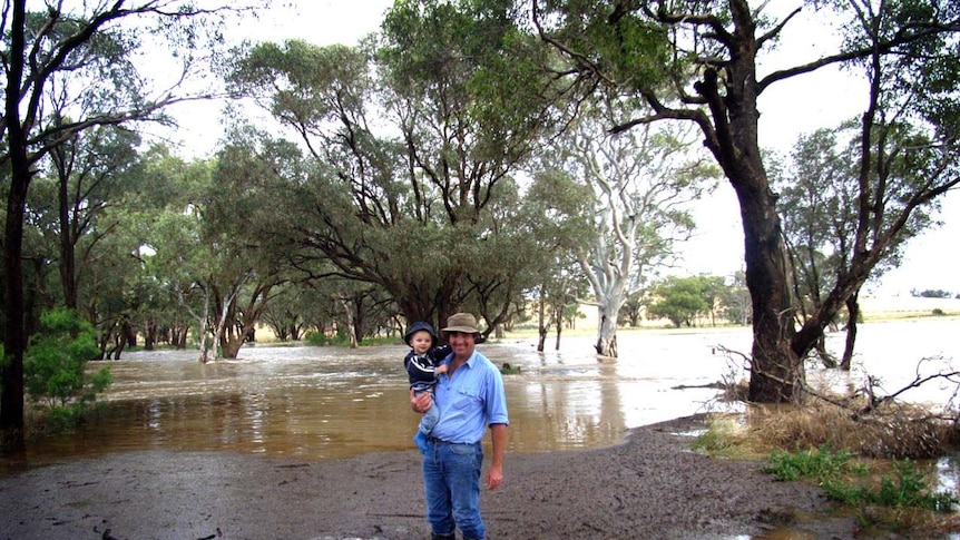 Robert Grimm stands in floodwaters with his son