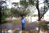 Robert Grimm stands in floodwaters with his son