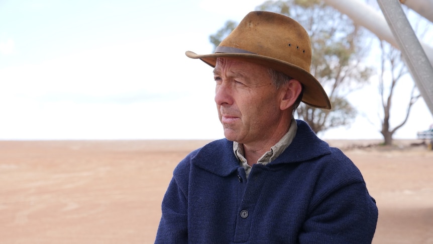 A farmer stares wistfully out at a grain field