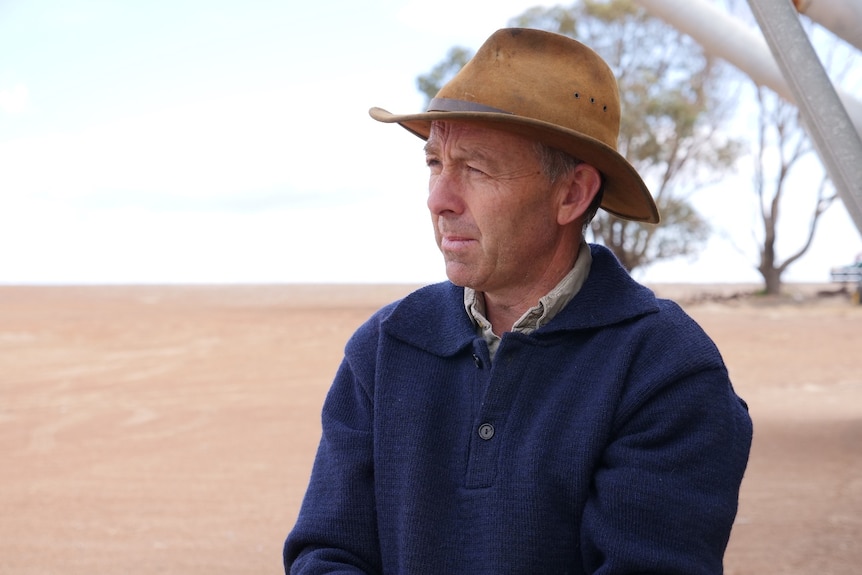 A farmer stares wistfully out at a grain field