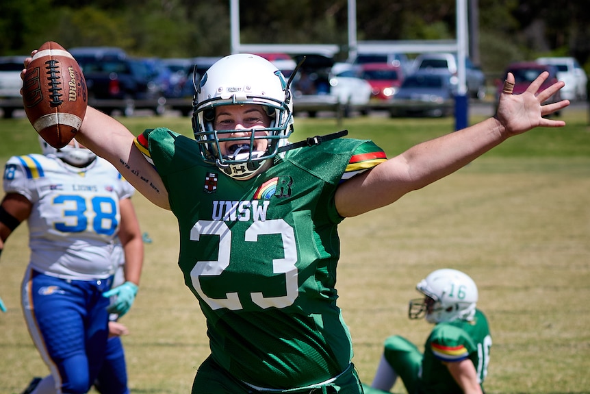 A UNSW Raiders women's player holds the ball with her arms out.